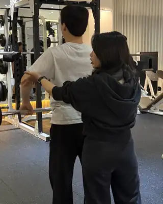 바벨을 든 회원의 팔과 어깨 움직임을 직접 잡아 주며 설명하는 윤혜영 트레이너